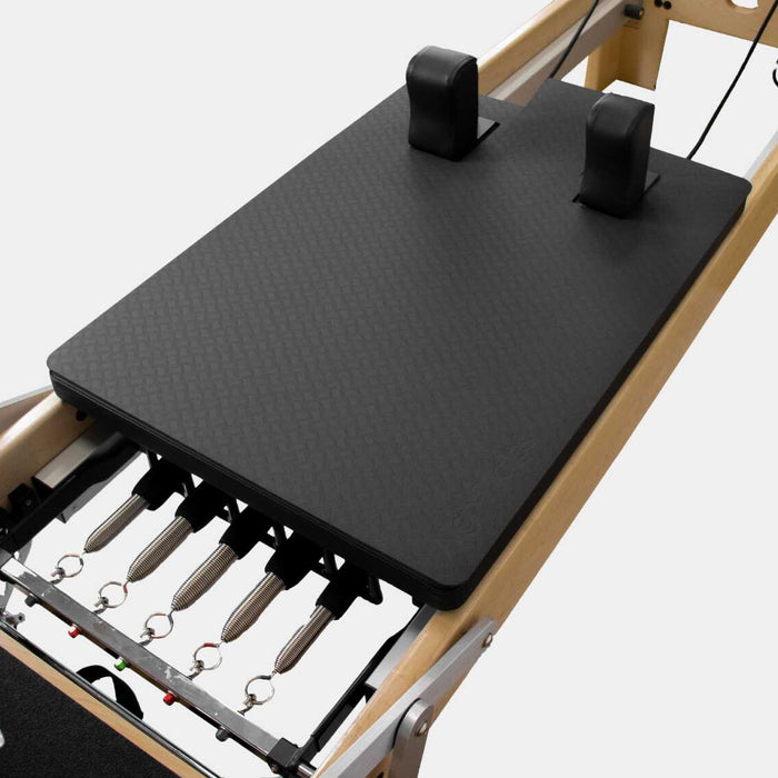 Black textured Align-Pilates M-Series carriage protector fitted around the shoulder rests on a wood-frame reformer.