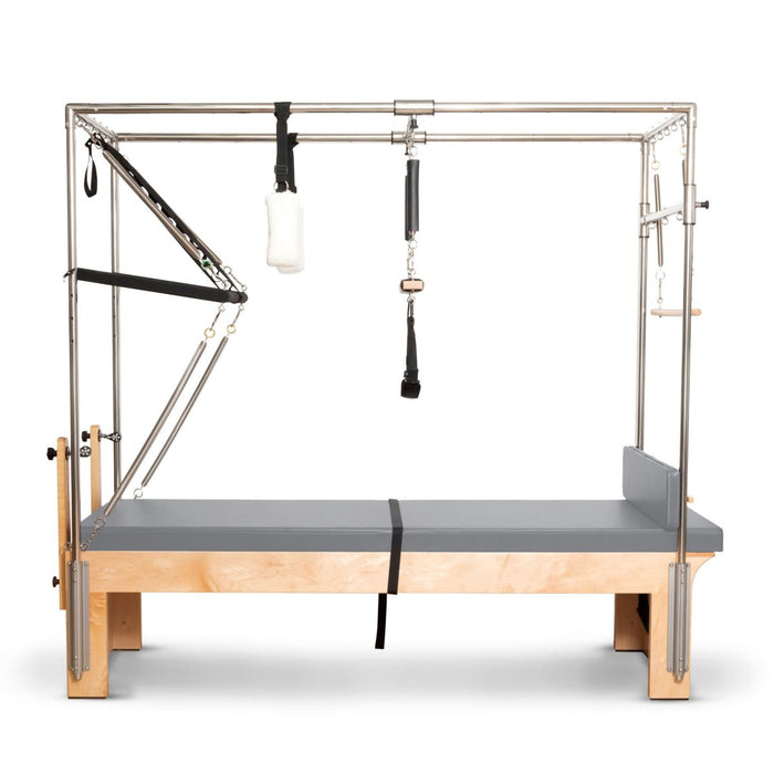 Elina Pilates Cadillac Reformer with grey padded mat surface, wood base, full overhead metal frame, trapeze and spring-loaded bars.