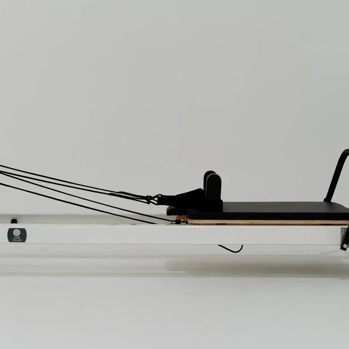 Core Collab Queen Studio reformer with white frame and black upholstery