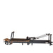 Space-saving Pilates reformer folded upright with wheels and locking system