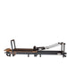 Space-saving Pilates reformer folded upright with wheels and locking system