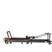 Space-saving Pilates reformer folded upright with wheels and locking system