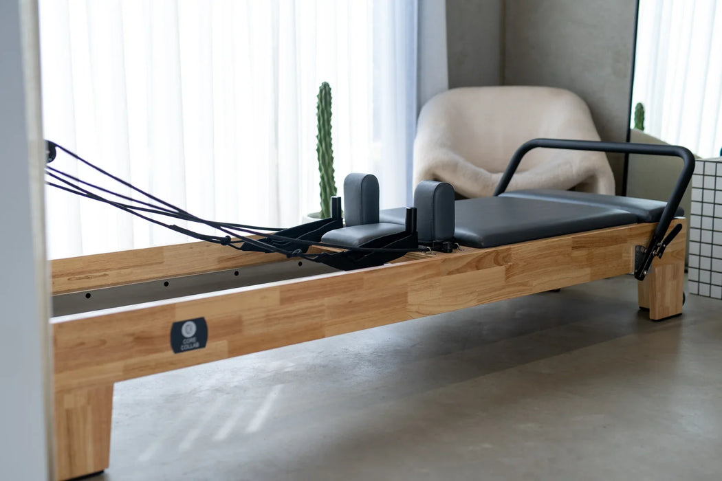 TCC Studio Eco Pilates Reformer - side profile view showing natural wood or eco-material frame construction